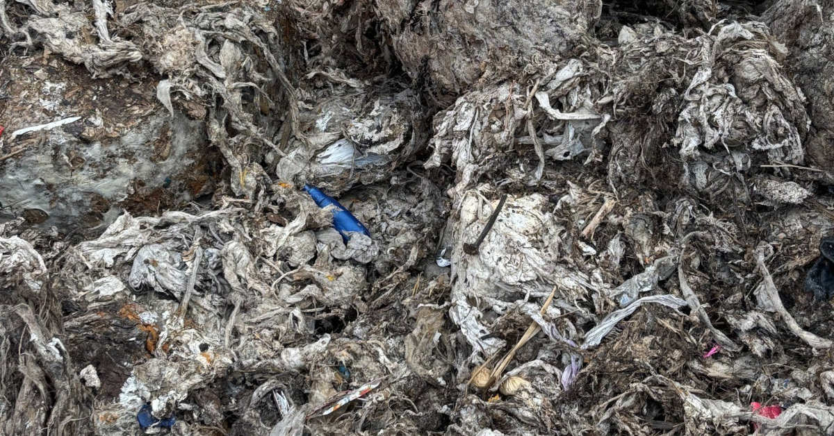 Grey pile of extracted wet wet wipes and other material with occasional plastic bottles